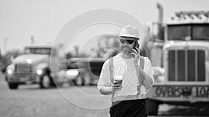 caucasian construction manager. mature architect in construction area. construction site with worker hold coffee at