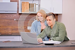 Caucasian couple discussing papers with laptop, man and woman roommates or husband and wife checking rent