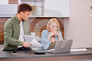 Caucasian couple discussing papers with laptop, man and woman roommates or husband and wife checking rent