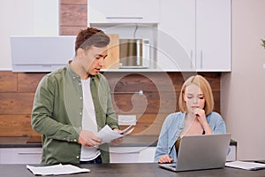 Caucasian couple discussing papers with laptop, man and woman roommates or husband and wife checking rent