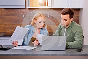 Caucasian couple discussing papers with laptop, man and woman roommates or husband and wife checking rent