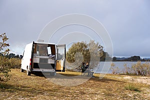 Caucasian couple eating breakfast on a lake with a camper van living van life social distancing on a Dam in Portugal