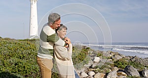 Caucasian couple enjoying free time by sea on sunny day embracing