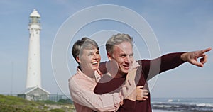 Caucasian couple enjoying free time by sea on sunny day pointing finger