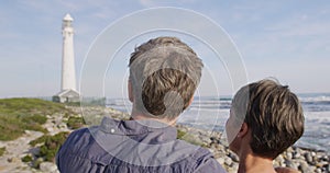 Caucasian couple enjoying free time by sea on sunny day pointing finger