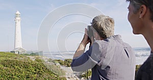 Caucasian couple enjoying free time by sea on sunny day taking photo with camera