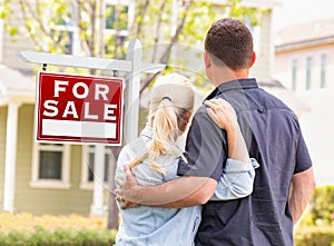 Caucasian Couple Facing Front of Sold Real Estate Sign and House