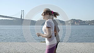 Caucasian couple jogging along sea, talking and smiling