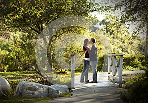 Caucasian couple kissing on outdoor wooden bridge