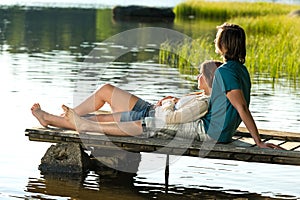 Caucasian couple lounging on pier sunset