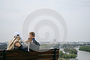 Caucasian couple in love sitting on wooden bench with a jack Russell terrier puppy and enjoying cityscape of Belgrade