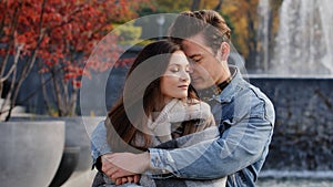 Caucasian couple lovers partners stand background of city fountain pressed closely to cheeks together spend time in