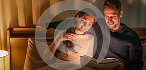 Caucasian couple lying on bed before bedtime and reading book together