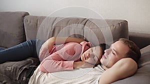 Caucasian couple lying on the sofa together at home embracing. Lovely girlfriend caressing his boyfriend. Relaxing on