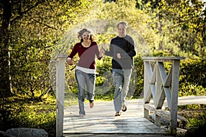 Caucasian couple running on bridge holding hands