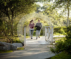 Caucasian couple running on outdoor wooden bridge