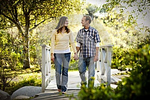 Caucasian couple walking on outdoor wooden bridge