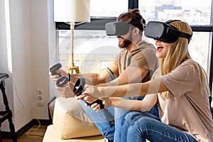 caucasian couple wearing Visual reality or VR headset playing video console game