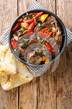 Caucasian cuisine Buglama lamb stewed with vegetables and herbs close-up in a bowl. vertical top view