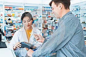 Caucasian customer purchases qualified prescription medication from pharmacist.