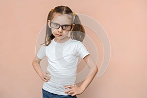 Caucasian cute girl 5 - 7 years old in a white T-shirt and jeans with diopter glasses, studio portrait