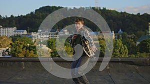 Caucasian dancer performing hip hop outside on the roof. Brunette man enjoying himself,looking at camera. Male showing