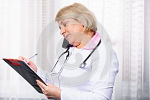 Caucasian doctor handsome woman with stethoscope talking on mobile phone, smartphone calls at clinic, checking healthcare of