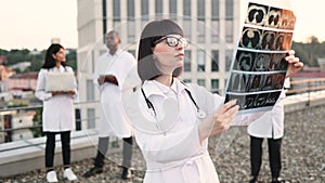 Caucasian doctor holding x-ray scan of patient during break outdoors hospital.