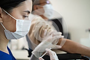 Caucasian Doctor or nurse woman wear protective face mask, holds injection syringe and squirting vaccine at nursing home care. The