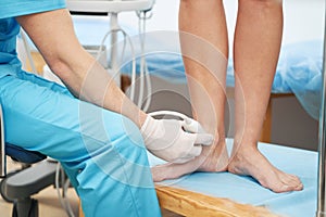 Caucasian doctor performing an ultrasound on young lady ankle joint