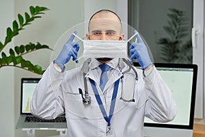 A caucasian doctor putting on a protective face mask to examine a patient