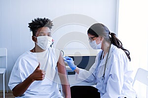 Caucasian doctor woman or nurse giving flu or antiviral vaccine to African American man in hospital or clinic