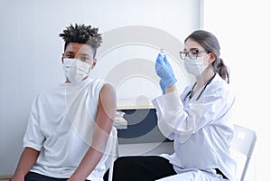 Caucasian doctor woman or nurse giving flu or antiviral vaccine to African American man in hospital or clinic