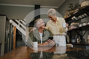 Caucasian elderly couple drinking coffee in kitchen