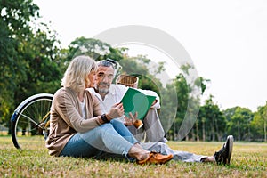 Caucasian elderly couple relaxing and sitting at the park reading the retirement plan to discussing together, happy marriage