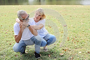 Caucasian elderly couple with white shirt, blue jean and sun glasses sitting and embracing in park during summer time on wedding