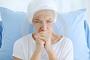 Caucasian Elderly Mother in white headscarf is laying on bed in hospital after chemotherapy because she is holding her hand for