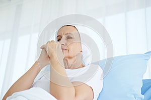 Caucasian Elderly Mother in white headscarf is laying on bed in hospital after chemotherapy because she is holding her hand for