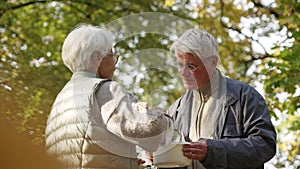 Caucasian elderly retired woman shares her homemade soup with jobless and homeless elderly man in need.