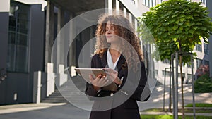 Caucasian elegant businesswoman curly hair girl lady young woman holding tablet typing on device outdoors smiling female