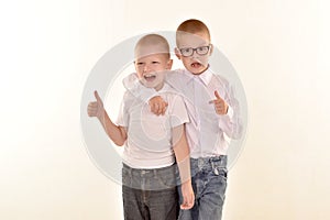 A caucasian elementary age boy with glasses posing in uniform isolated on white background with him brother. School and education