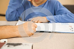 Caucasian elementary school child doing homework at the end of the school day with parental help and support.