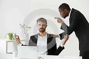 Caucasian employee meditating at workplace ignoring angry boss s