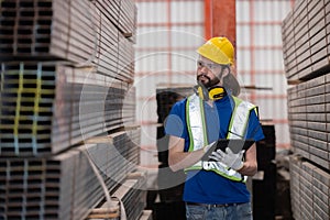 Caucasian engineer inspect steel bars with tablet in a factory