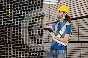 Caucasian engineer inspect steel bars with tablet in a factory