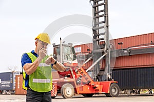 Caucasian engineer standing in front of Reach stacker vehicle in shipping yard