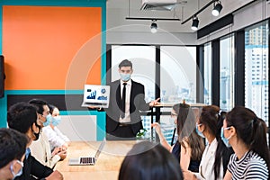 Caucasian executive businessman wearing face mask with presentation of business plan by laptop, corporate business meeting with