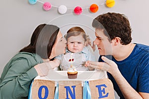 Caucasian family with baby boy celebrating his first birthday at home. Proud parents mother and father dad together with child kid