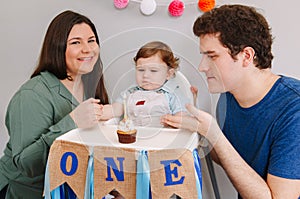 Caucasian family with baby boy celebrating his first birthday at home. Proud parents mother and father dad together with child kid