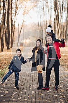 Caucasian family goes for a walk in the autumn park with two children